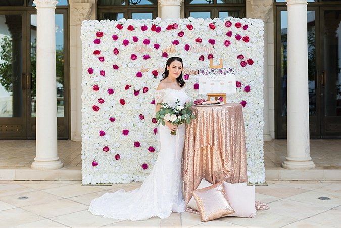 Bride posing against flower wall. 