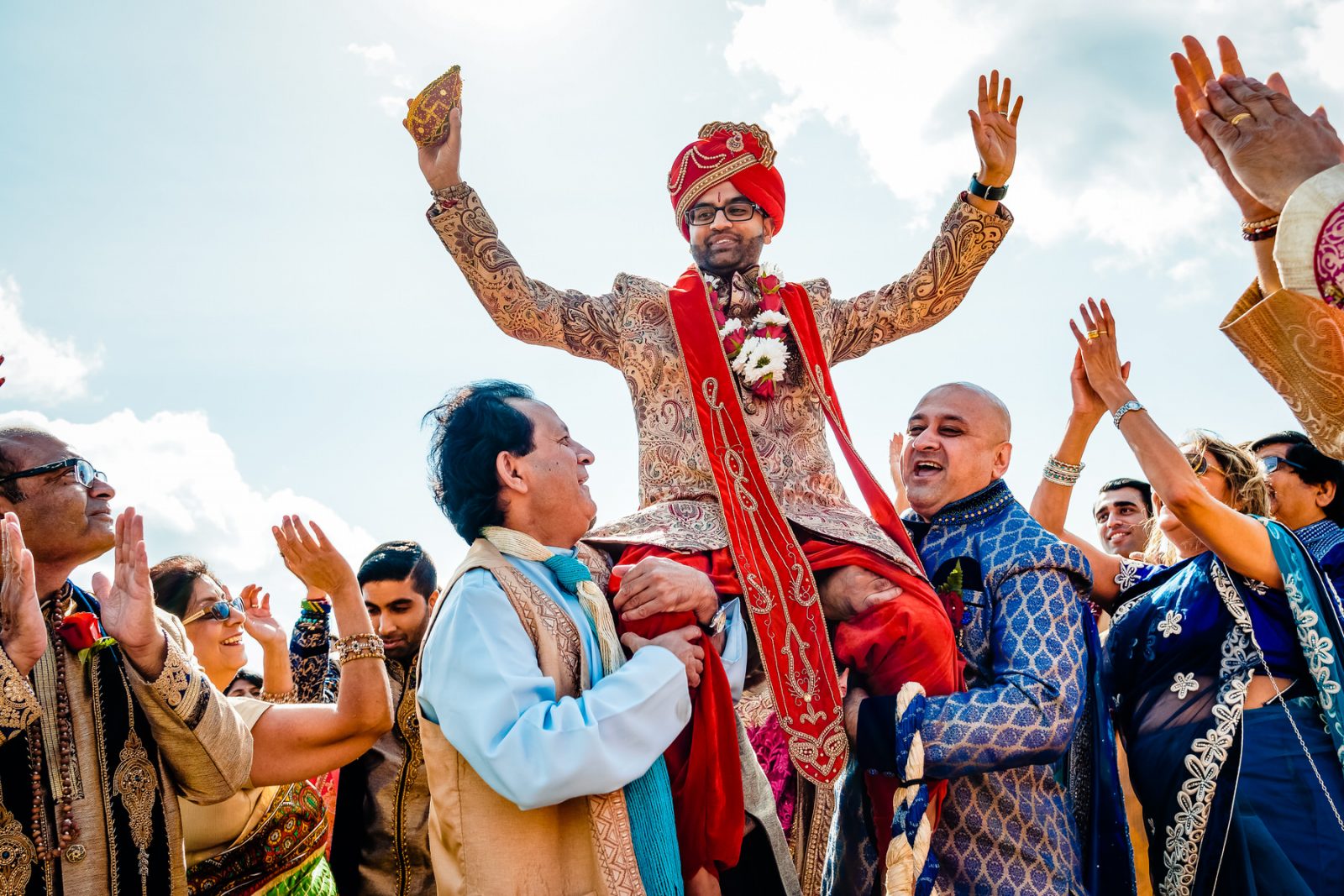 Indian Groom being lifted up by family at wedding